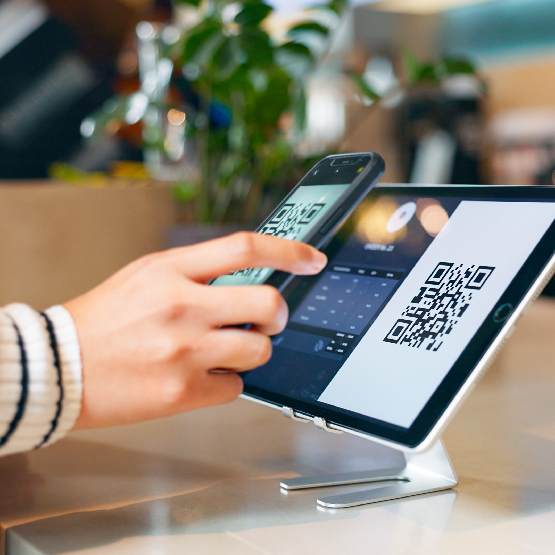 hand holding a phone that is scanning a QR code on an tablet