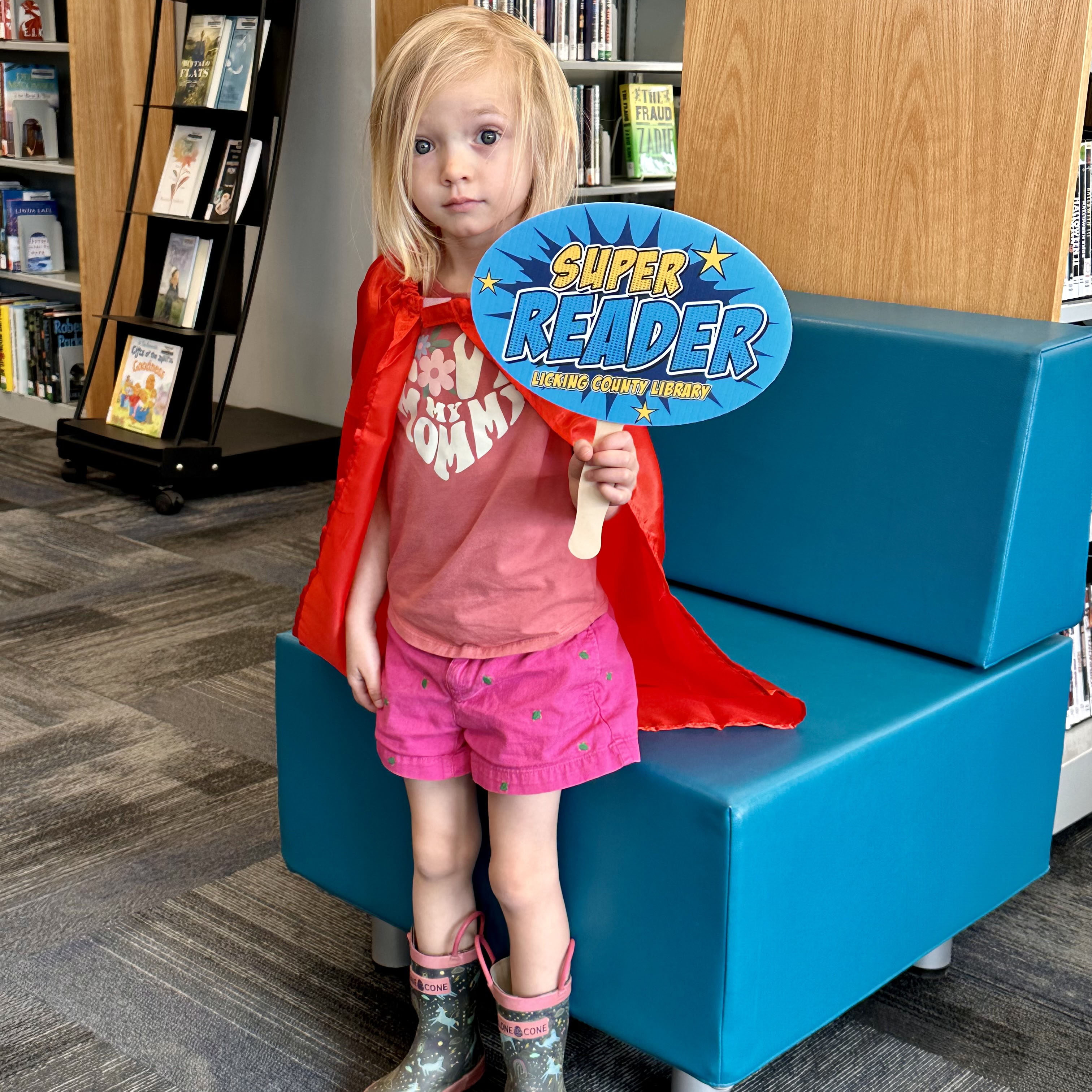 1000 Book recipient with cape and holing super reader sign